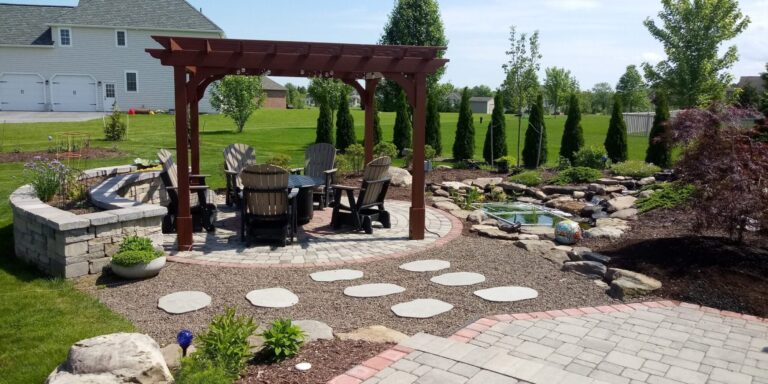 Wood pergola shading chairs on a circular paver patio with stepping stones, seat wall and backyard pond in York PA