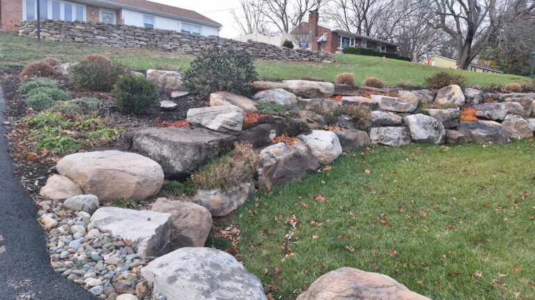 Tiered boulder retaining wall planted with hardy groundcovers on a front slope in York PA, shown in late fall.