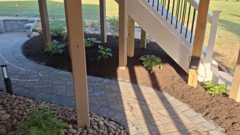 Two paver paths meeting in a shade garden with lush shade plantings beneath a deck stairway in York PA.