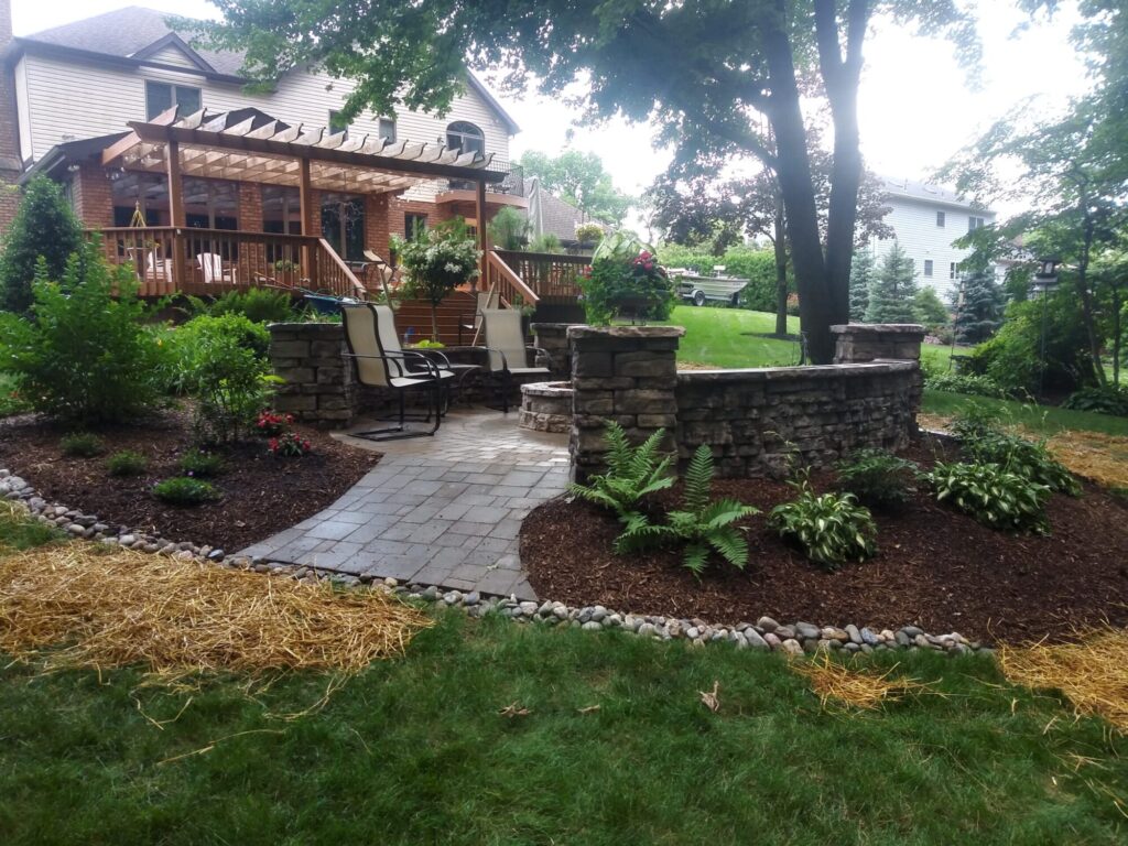 Paver walkway edged in river rock leading past lush shade plantings to a stone fire pit patio in York PA.