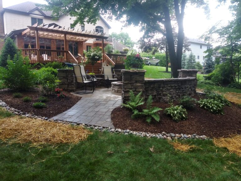 Paver walkway edged in river rock leading past lush shade plantings to a stone fire pit patio in York PA.