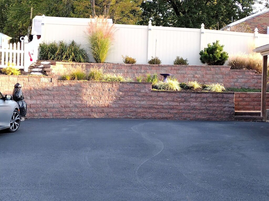 Freshly mulched and pruned planting beds along a stone wall